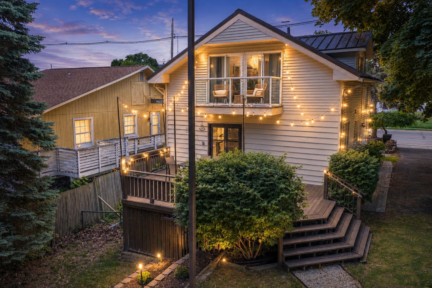 Washington House at dusk with a glowing private balcony, elevated deck, and leafy backyard